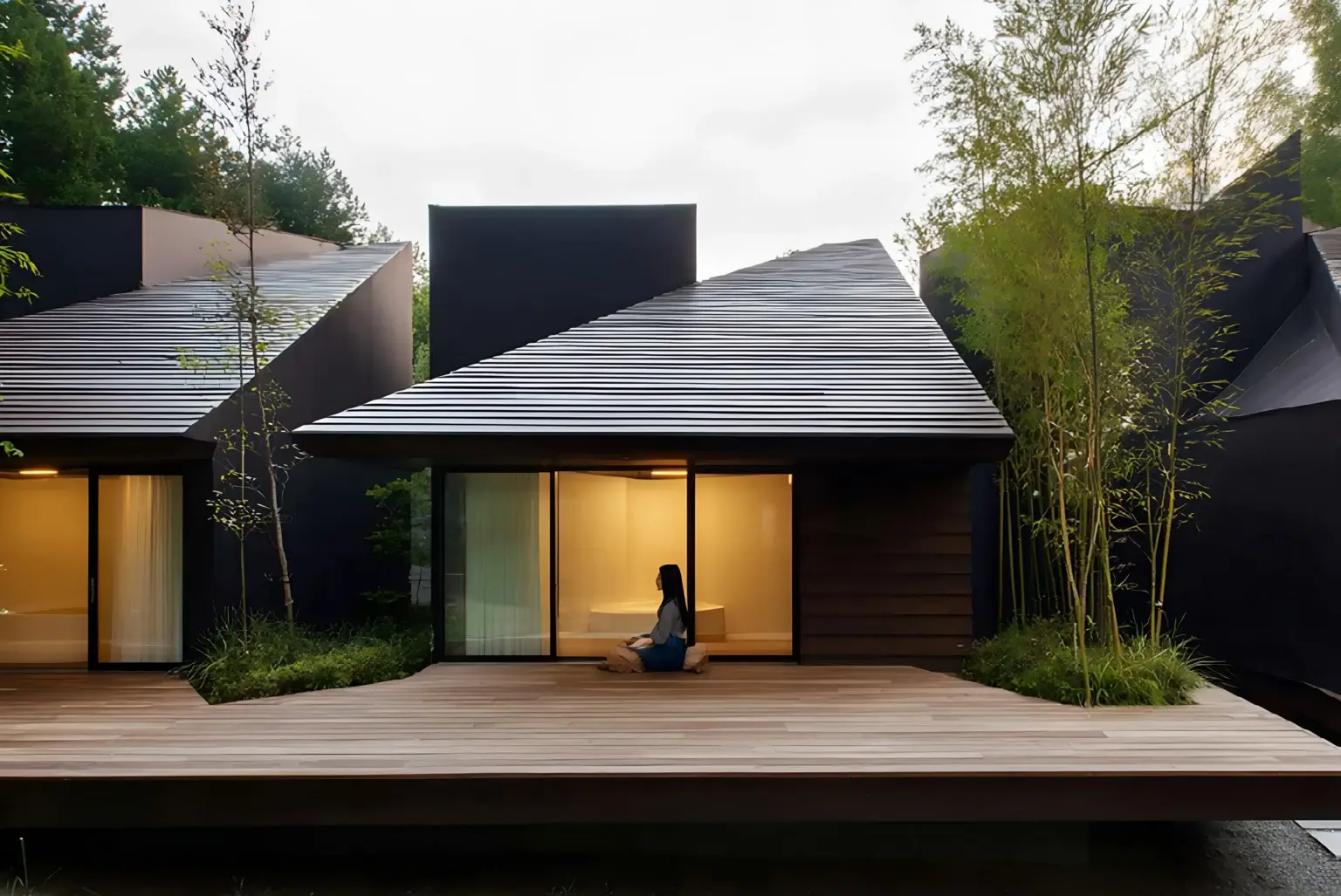 Modern sustainable home with dark wood cladding, angled roofline, large glazing, and native landscaping blending into the surrounding trees